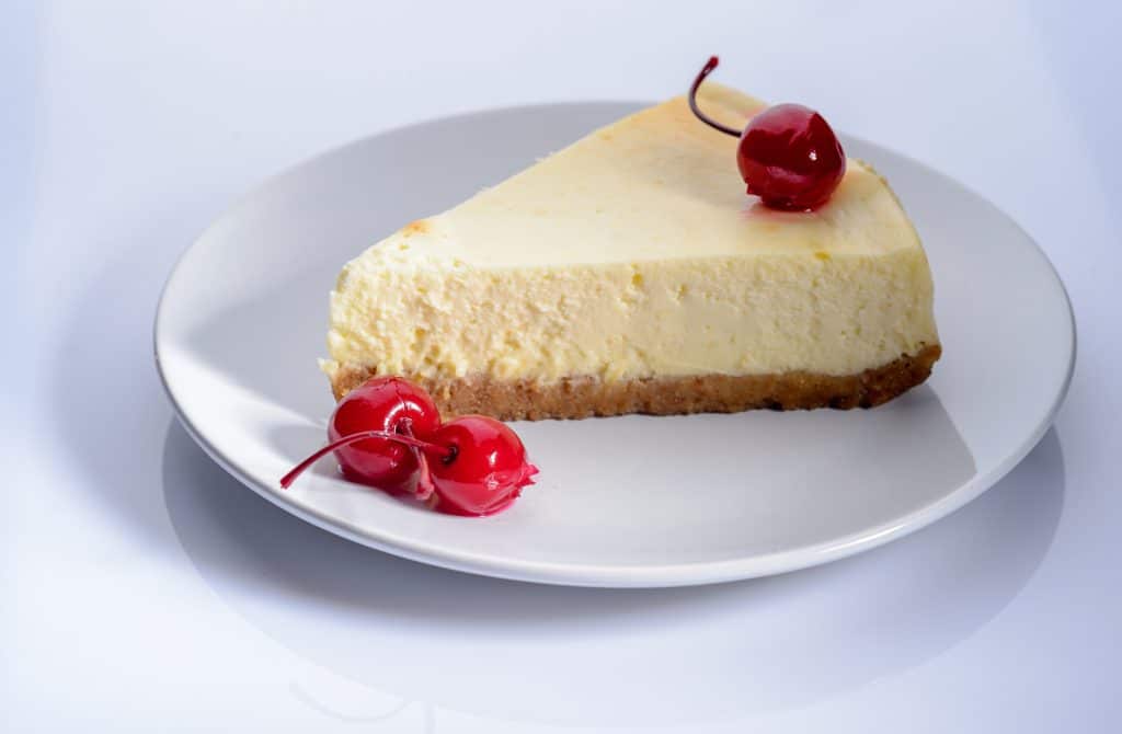 a slice of cheesecake with cherry on a plate