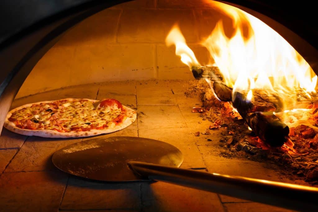 cooking pizza in a firewood oven