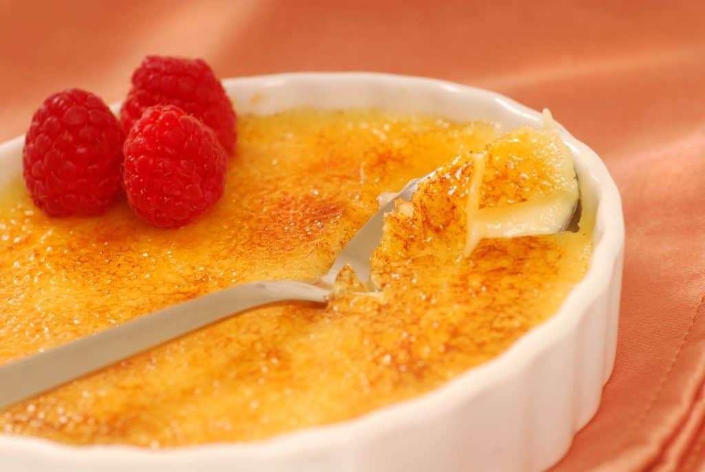 creme brulee with raspberries in a white bowl