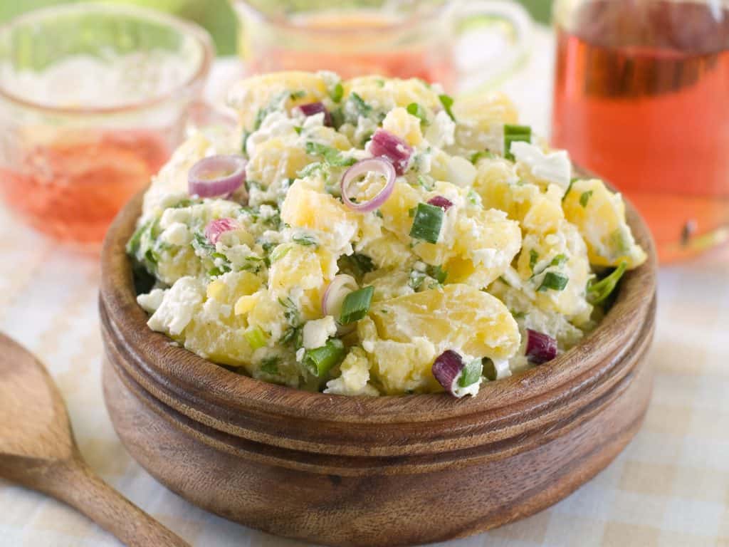 potato salad with mayonnaise and spring onion in a wooden bowl