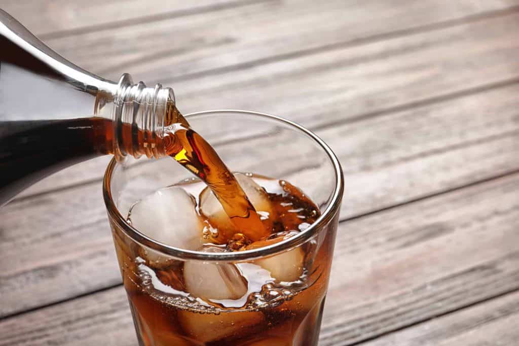 pouring coke into a glass with ice