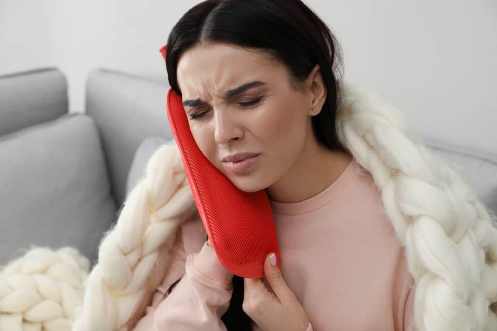 woman using hot water bottle to relieve neck pain