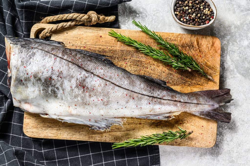 fresh haddock fish with rosemary on a cutting board