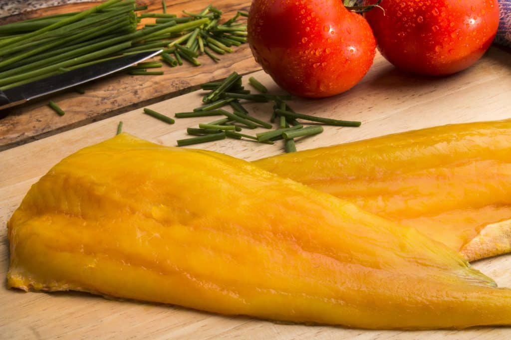 smoked haddock fillet, tomato and chive in a cutting board 
