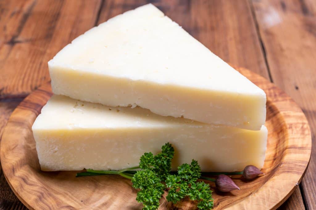 two slices of pecorino romano cheese with herb on a wooden plate