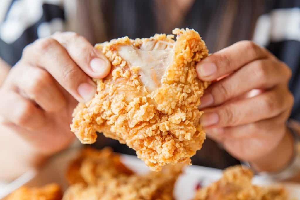 woman holding fried chicken and eating in the restaurant