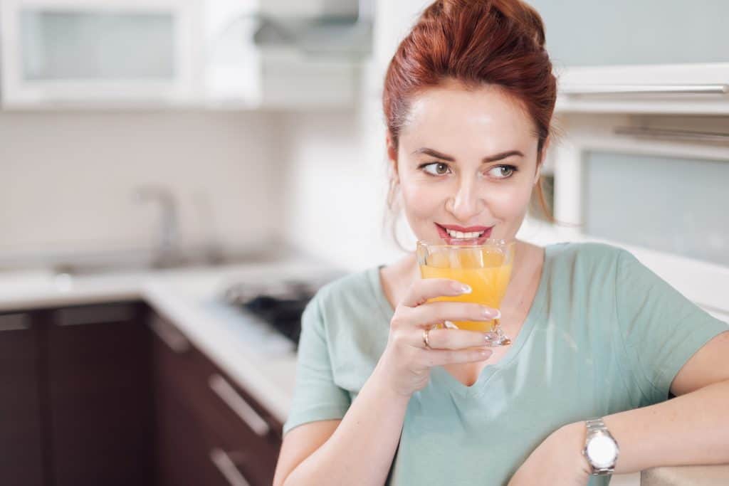 Smiling woman drinking a glass of emergen-c